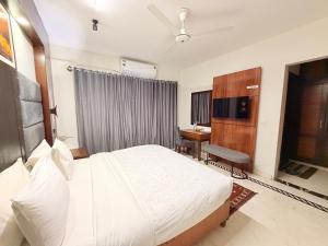 a bedroom with a large white bed and a desk at Comfort Lodge Executive in Islamabad