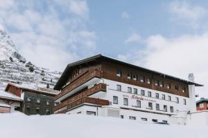 a building in the snow in front of a mountain at Hotel Hirlanda in Zürs am Arlberg