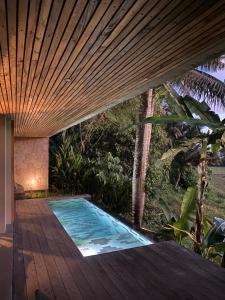ein Swimmingpool in einem Haus mit Holzterrasse in der Unterkunft Soma Beach House in Balian