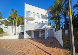 a white house with palm trees in front of it at The White House at Plattekloof in Plattekloof