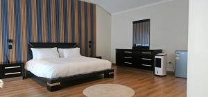 a bedroom with a bed and a dresser and a television at The White House at Plattekloof in Plattekloof