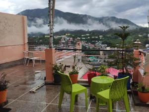 a balcony with green chairs and a view of a city at Solan Regency in Solan +23 photos