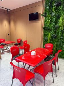 a restaurant with red tables and chairs and a green wall at Хостел Ганга in Tashkent