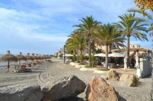 piaszczystą plażę z palmami i parasolami w obiekcie Los Miradores Del Puerto - 5207 w mieście La Manga del Mar Menor