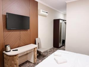 a hotel room with a desk and a tv on a wall at DeLuxe PLAZA in Almaty +40 photos
