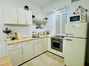 a kitchen with white cabinets and a white refrigerator at St Peter's Heritage House in Trogir