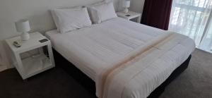 a bedroom with a large bed with white sheets and pillows at Spacious big sea views star bath in Paihia