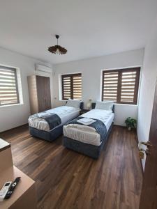 two beds in a room with wooden floors and windows at Къща за гости Старлес in Malko Tŭrnovo