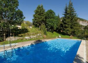 a large blue swimming pool with trees in the background at La Terraza de Escarrilla, con piscina in Escarrilla