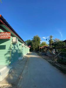 an empty street next to a green building at Don Det SODA RiverSide Guesthouse in Ban Donsôm Tai