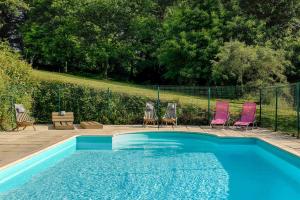 a swimming pool with two chairs and a table at FORET TOTEM - Hébergements nature et bien-être en pleine forêt in Persquen