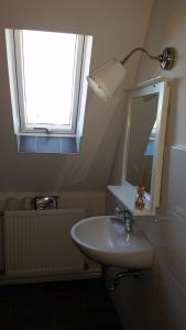 La salle de bains est pourvue d'un lavabo, d'un miroir et d'une fenêtre. dans l'établissement Pension Altes Forstamt, à Eberswalde-Finow