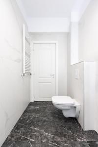 a white bathroom with a toilet and a door at Luxury Elegant Pipera New Apartment in Voluntari +3 photos