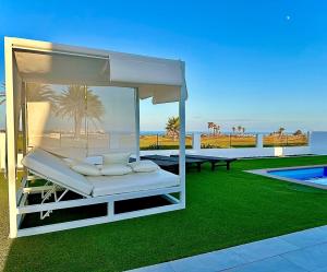 a white canopy bed on a lawn next to a pool at Vila Al Mar in Caleta De Fuste