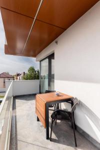 a patio with a wooden table and chairs on a balcony at Luxury Elegant Pipera New Apartment in Voluntari
