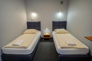 two twin beds in a room with a table at Hotel Maraton in Kielce