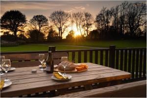 a wooden table with a bottle and glasses of wine at Olive Lodge Benllech in Brynteg +24 photos