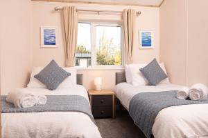 two beds in a room with a window at Olive Lodge Benllech in Brynteg