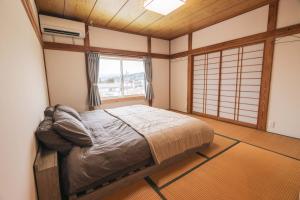 a bedroom with a bed in a room with a window at Myoko Yuki House in Myoko