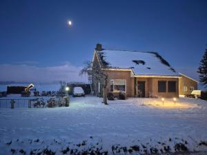 a house covered in snow at night with the moon at De Morgenzon in Waspik