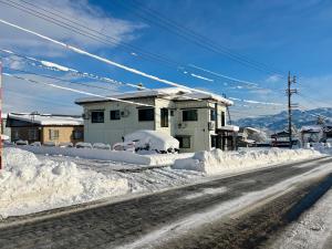 a street covered in snow next to a house at Myoko Yuki House in Myoko