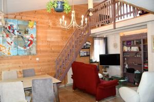 a living room with a staircase and a red chair at Gîte Le Cincle au cœur du massif des Vosges in La Bresse