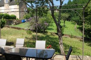 a table and chairs with a view of a garden at Gîte Les Noyers in Noailhac