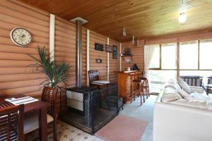 a living room with a wood paneled wall with a fireplace at Chloes Cabin Accommodation in White Beach