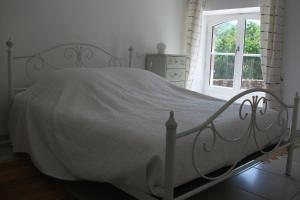a white bed in a white bedroom with a window at Gîte Les Noyers in Noailhac