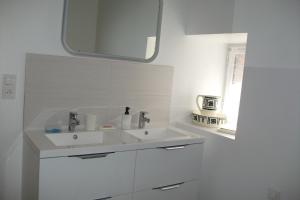 a white bathroom with a sink and a mirror at Gîte Les Noyers in Noailhac +6 photos