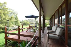 a wooden deck with chairs and an umbrella at Chloes Cabin Accommodation in White Beach