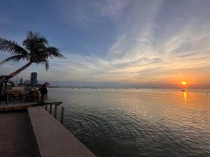 a person standing on a pier near the water with a palm tree at Papa House Standard Zone A in Ban Bang Saen (1) +4 photos