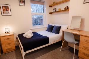a bedroom with a bed and a desk and a window at Gloucester 5 Bedroom Cosy Home-Work or Leisure in Gloucestershire