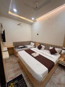 a bedroom with two beds and a television in it at Shree Guru Ashray in Ujjain