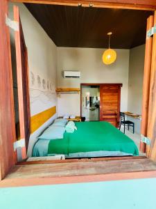 a bedroom with a large bed with a green comforter at Recanto do cajueiro in Flecheiras