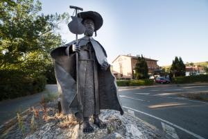 Eine Statue eines Mannes mit einem Regenschirm auf der Straße. in der Unterkunft Albergue Jakue in Puente la Reina