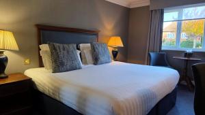 a hotel room with a large bed and a window at Windmill Village Hotel, Golf Club & Spa, BW Signature Collection in Coventry