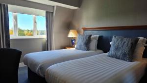 a hotel room with two beds and a window at Windmill Village Hotel, Golf Club & Spa, BW Signature Collection in Coventry +50 photos