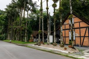 a building with palm trees in front of a street at Casa Enxaimel em Pomerode SC 01 in Pomerode