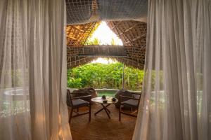 a room with a table and chairs and a window at Bamboo Zanzibar in Jambiani