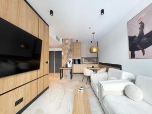 a living room with a white couch and a tv at Apartament - Vidok 301 in Olsztyn