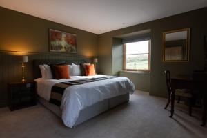 a bedroom with a bed and a desk and a window at Luxury Farmhouse, near Dornoch in The Mound