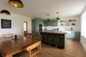 a kitchen with a wooden table and a dining room at Luxury Farmhouse, near Dornoch in The Mound