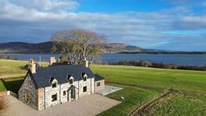 an aerial view of a house in a field next to a lake at Luxury Farmhouse, near Dornoch in The Mound