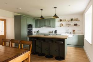 a kitchen with green cabinets and a wooden table at Luxury Farmhouse, near Dornoch in The Mound +17 photos