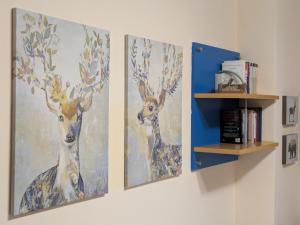 three paintings of deer on a wall with a shelf at Appartamento Cedro - Centro Aprica - Park - WiFi in Aprica