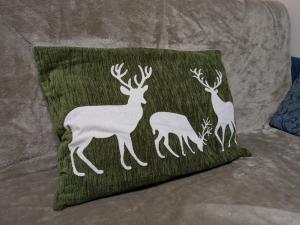 a green pillow with deer on it on a couch at Appartamento Cedro - Centro Aprica - Park - WiFi in Aprica