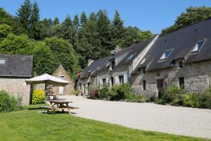 a picnic table next to a row of stone buildings at FORET TOTEM - Hébergements nature et bien-être en pleine forêt in Persquen