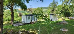 two mobile homes in a yard with trees at Petit a Petit - gypsy wagons and Bell tents in the Bourgogne in Saisy