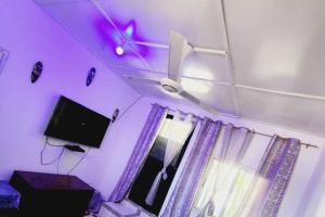 a purple room with a tv and a ceiling fan at Inviting 1-Bed House in Brusubi in Brusubi